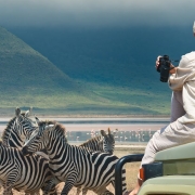A tourist sitting on the bonnet of a Safari truck in the Ngorongoro Conservation Area