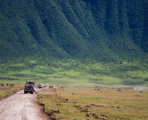 4x4 Safari trucks close to the steep walls of the Ngorongoro crater
