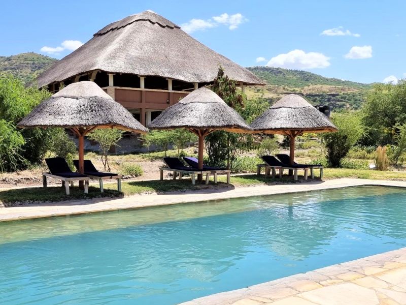The swimming pool of Africa Safari Lake Natron with the Restaurant in the background