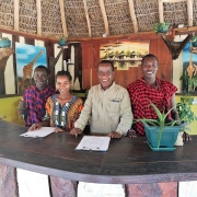 Staff members pose for a group photo behind the counter of the reception in Africa Safari Selous Lodge