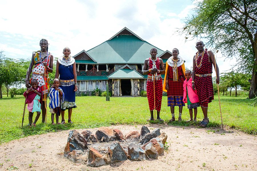 Several Maasai dressed in their traditional colorful shukas pose in front of the main building of Africa Safari Serengeti Ikoma